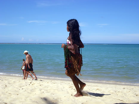 Niña pataxó vendiendo collares en la playa